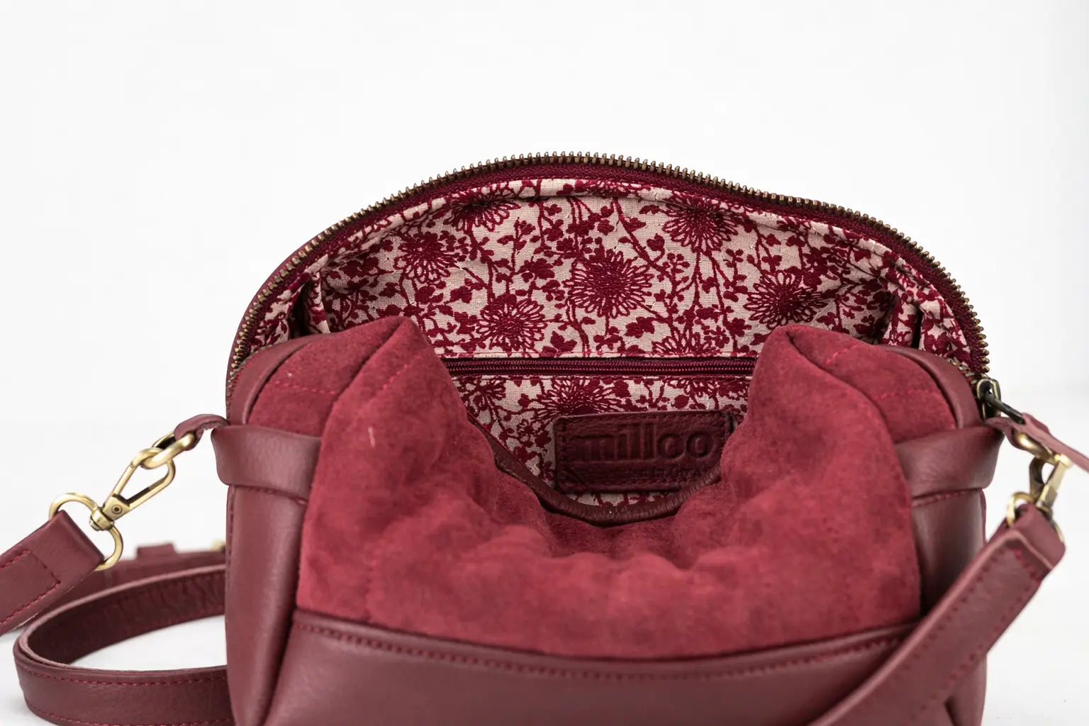 Maroon handbag with floral patterned interior on a white background