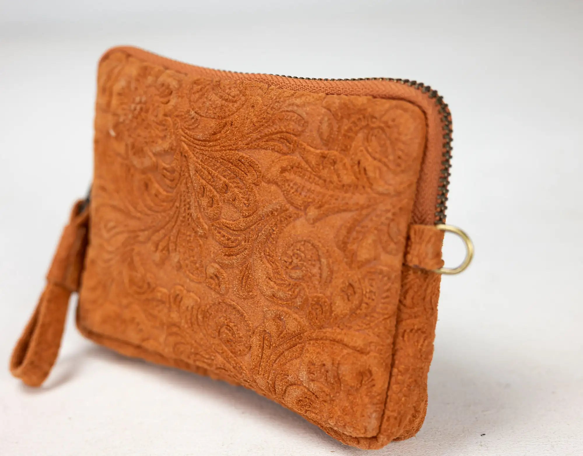 Brown leather clutch with intricate patterns on a white background