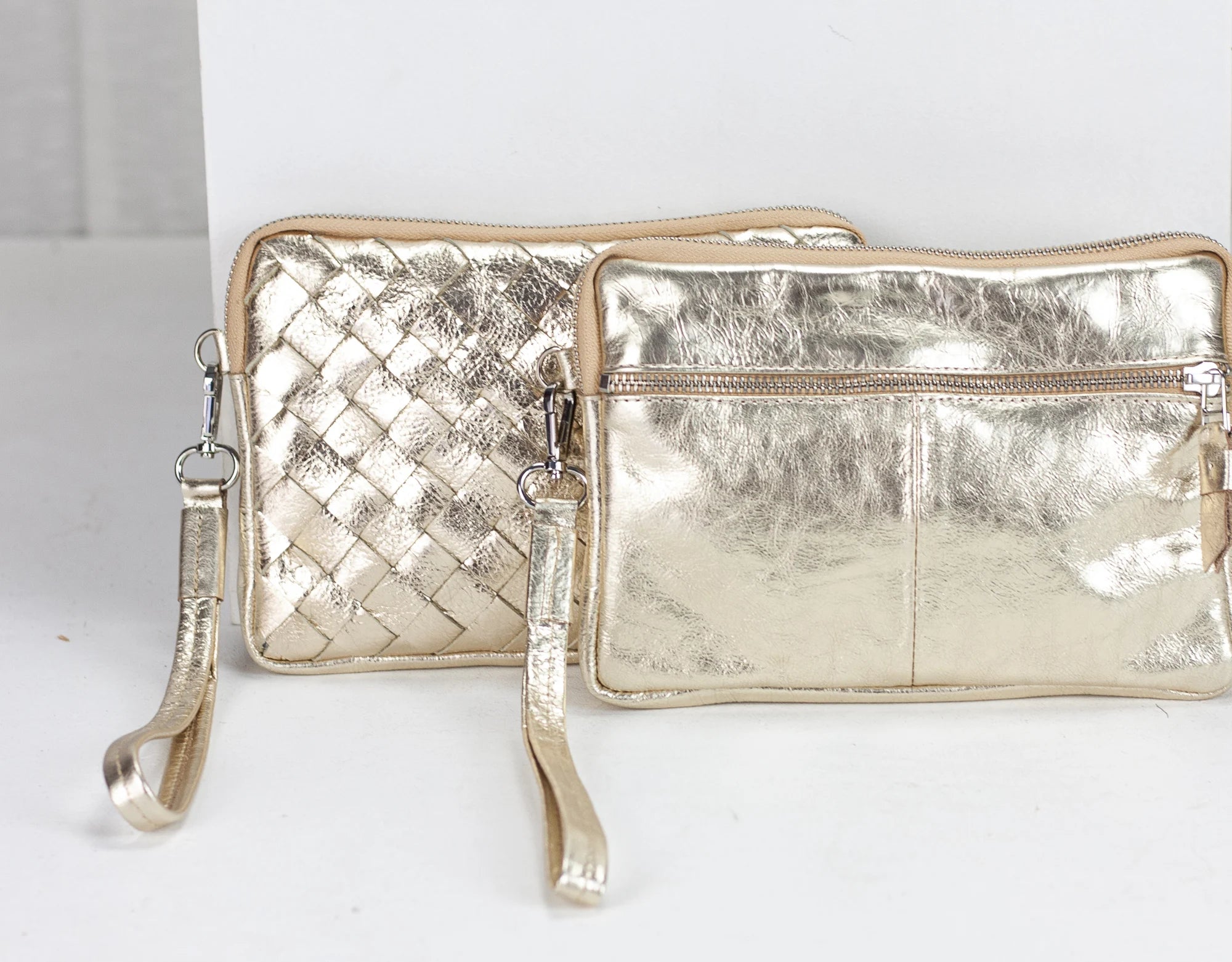 Two metallic gold handbags on a white background