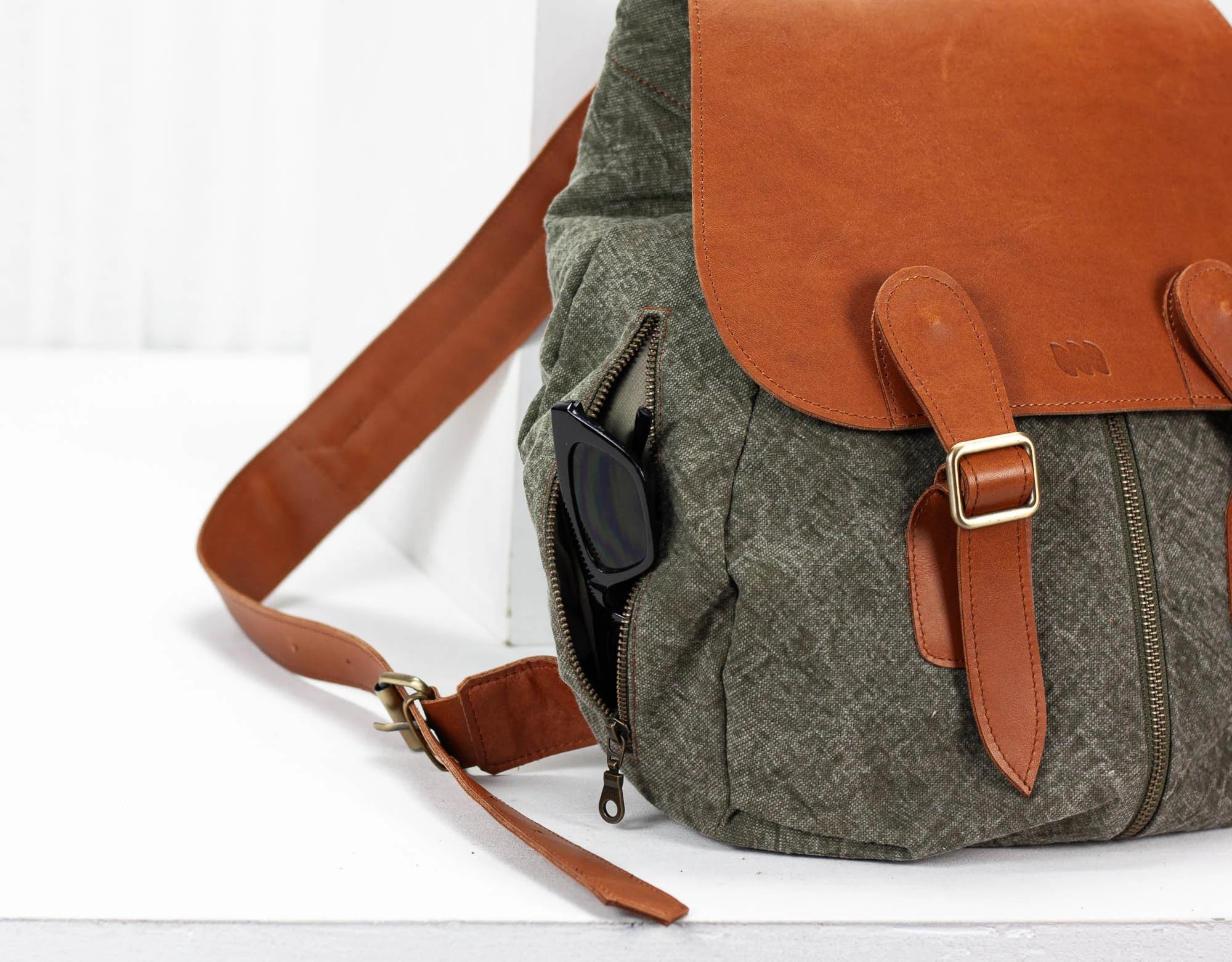 green backpack with brown leather accents on a white background