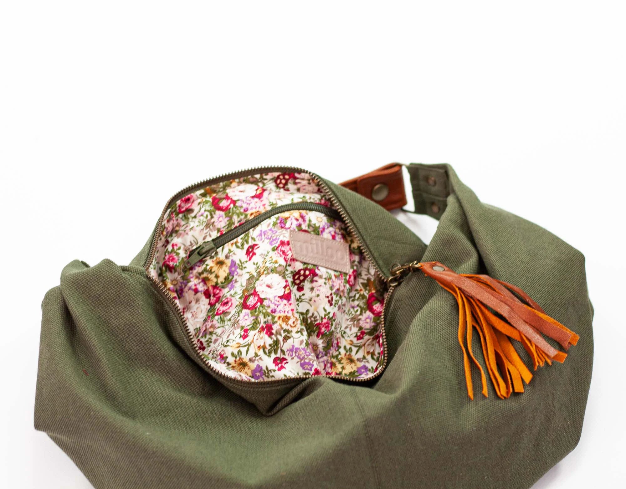 Green bag with floral pocket and orange tassel on a white background