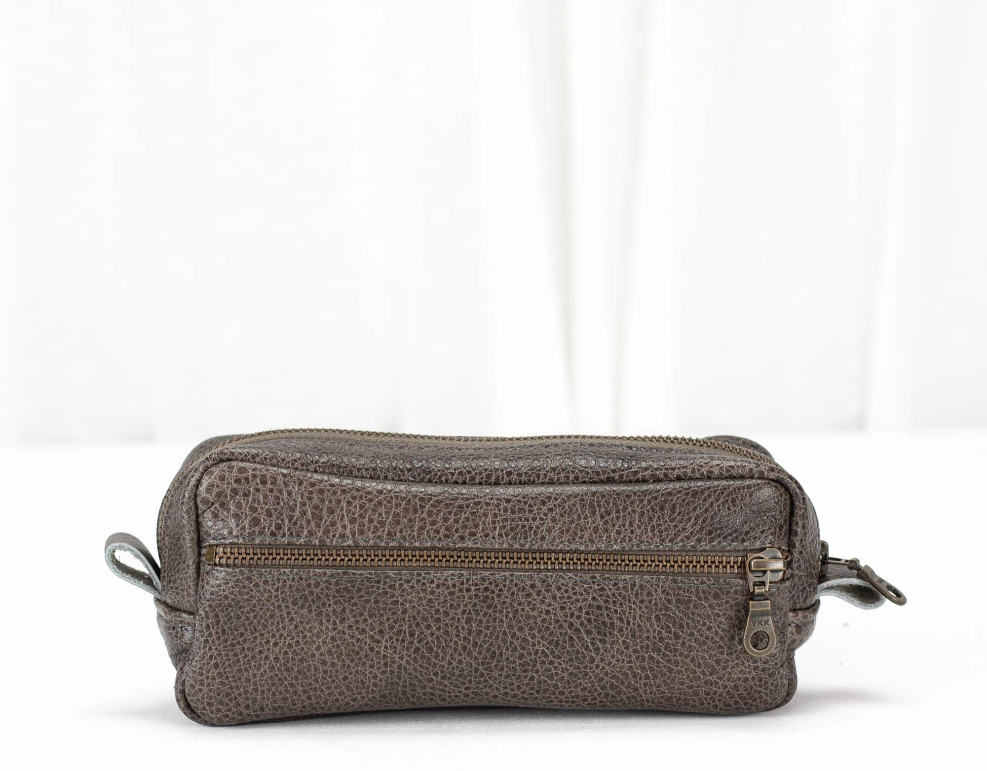 grey leather toiletry bag with a zipper on a white background