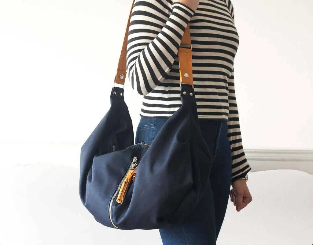 Person wearing a navy blue handbag with yellow accents on a white background