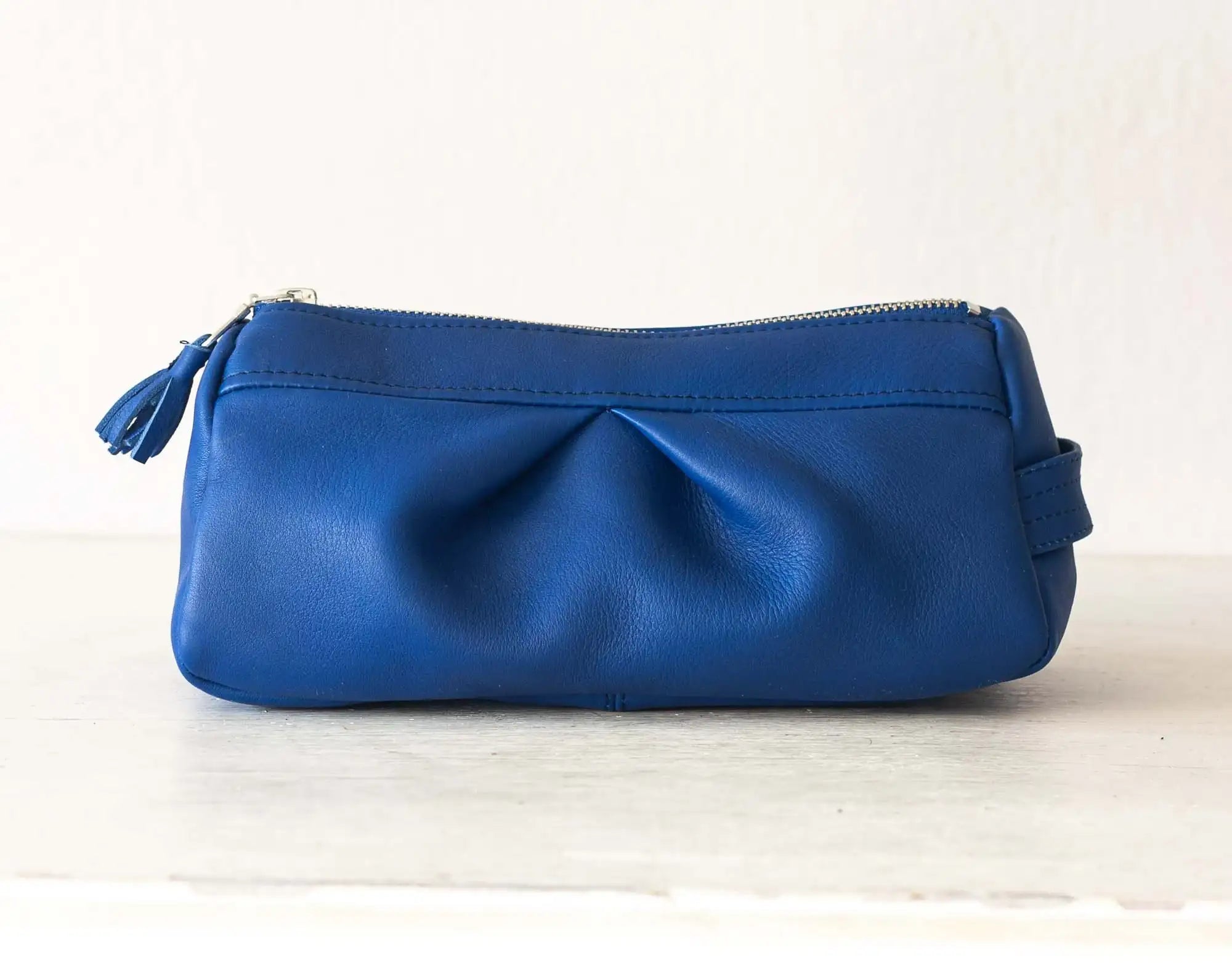 Blue leather pouch on a light wooden surface with a white background