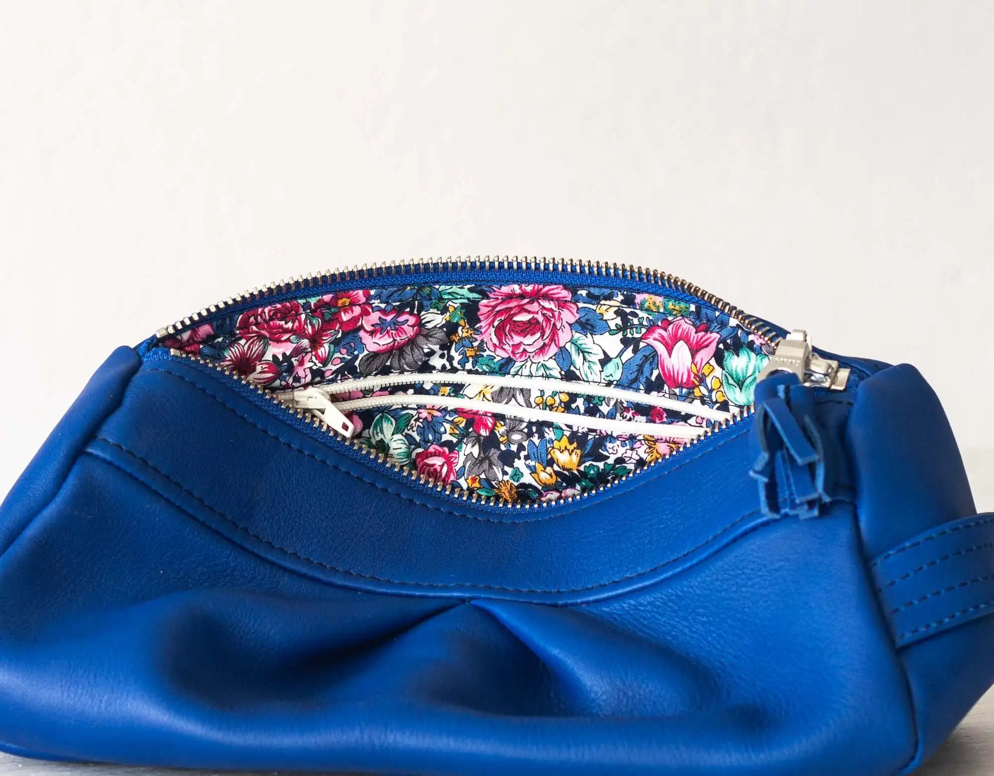 Blue handbag with floral interior on a light gray background