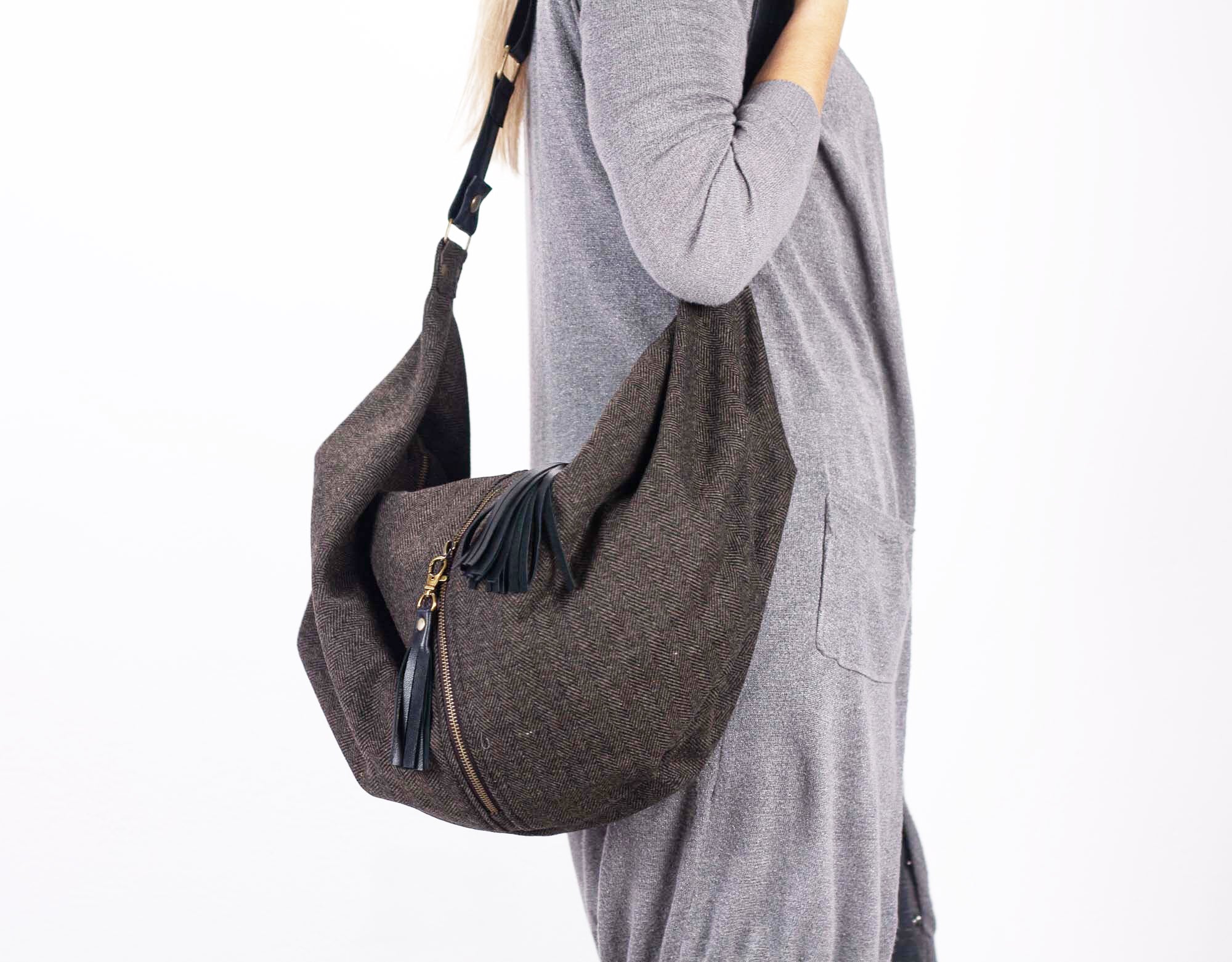 Person wearing a gray sweater with a brown hobo bag on a white background