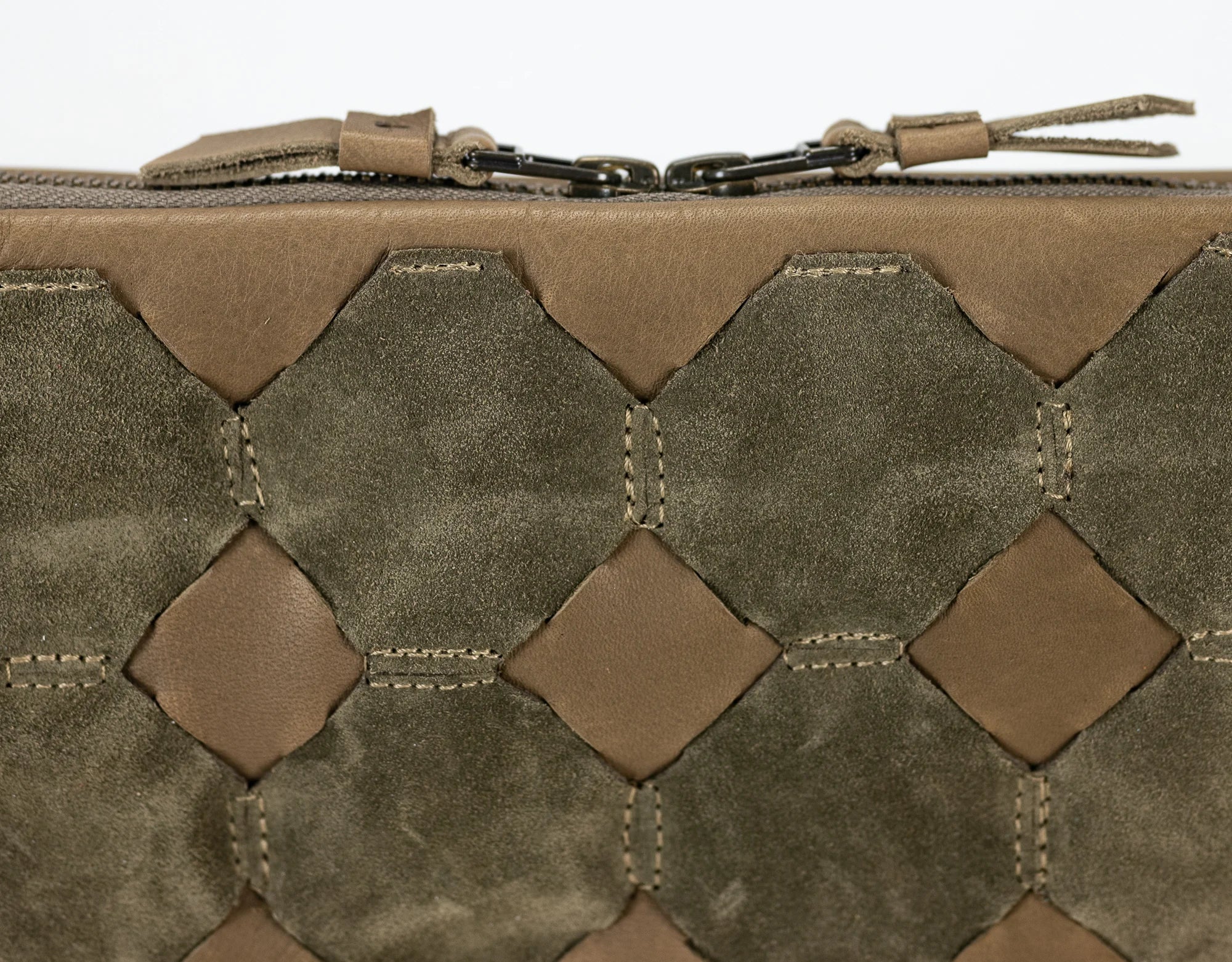 Close-up of a brown leather pouch with geometric pattern and brand logo.