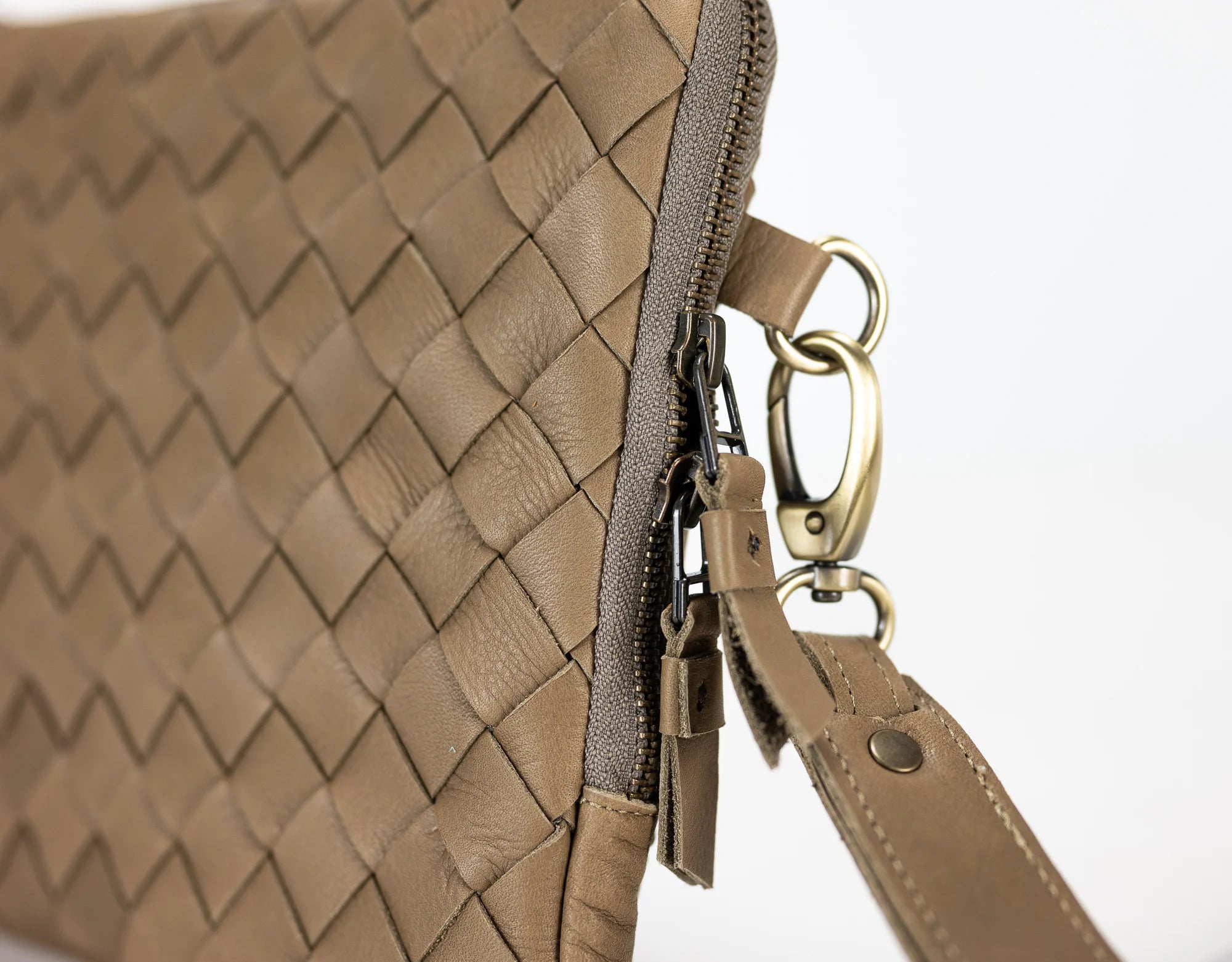 Close-up of a beige woven handbag with a gold clasp on a white background