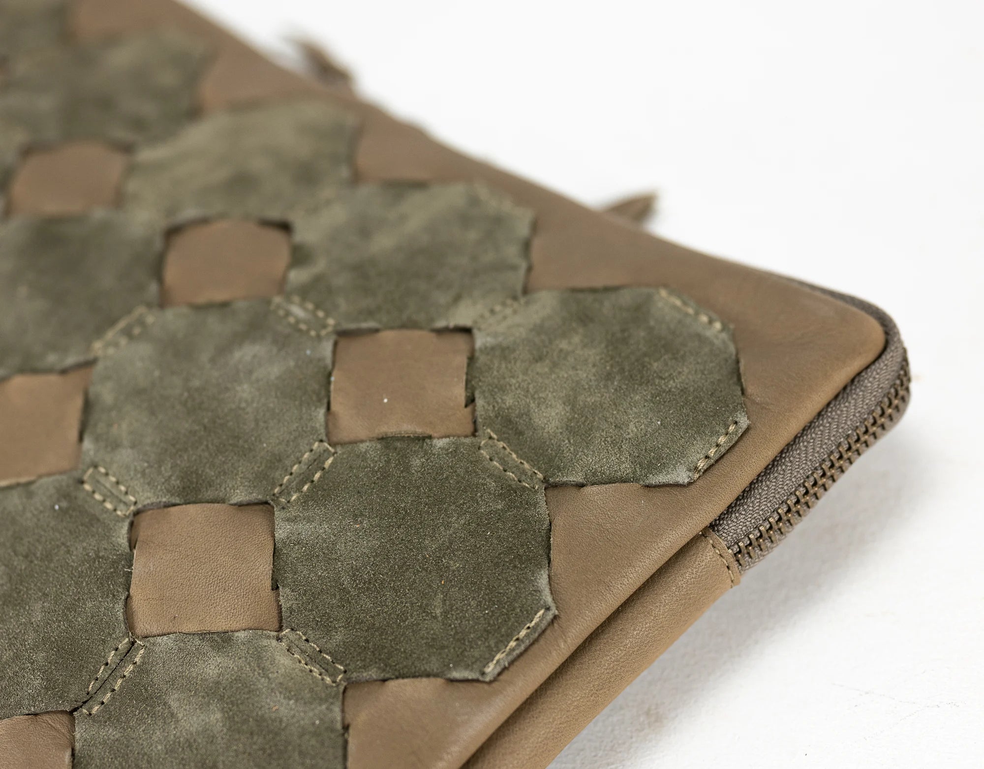 Close-up of a brown leather pouch with hexagonal pattern on a white background