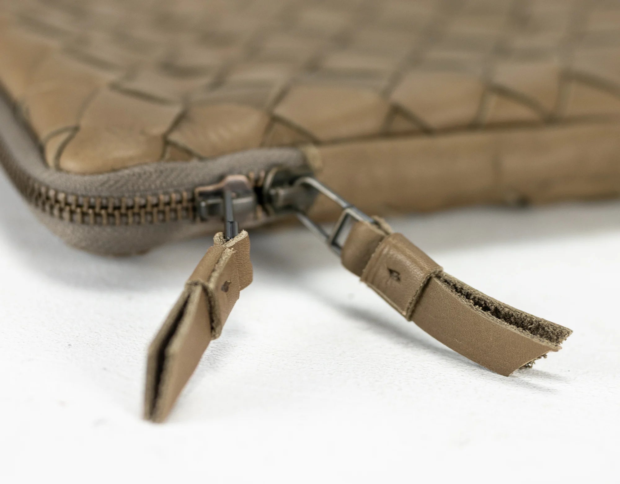 Close-up of a brown leather bag with a zipper on a white background