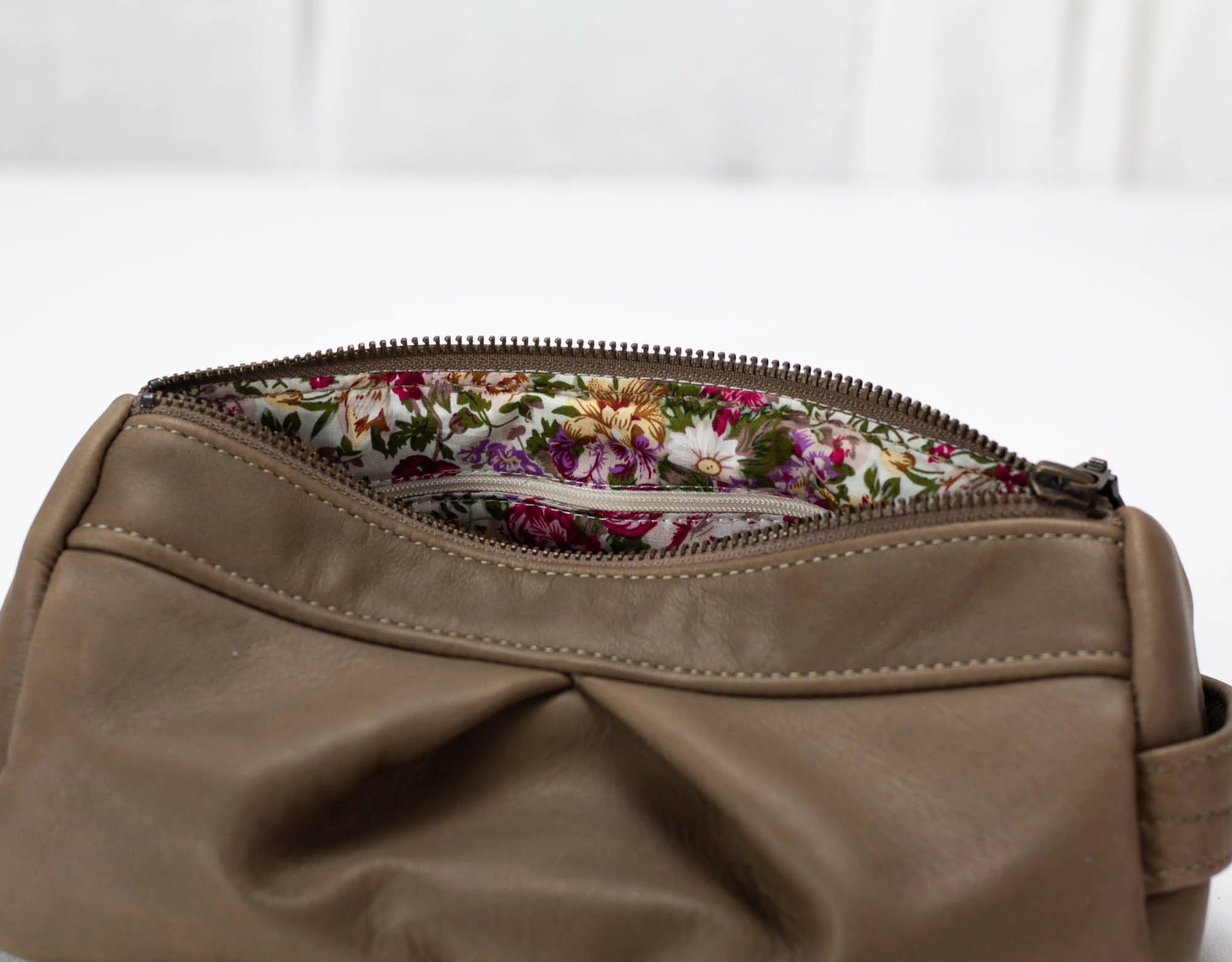 Brown leather bag with floral lining on a white background