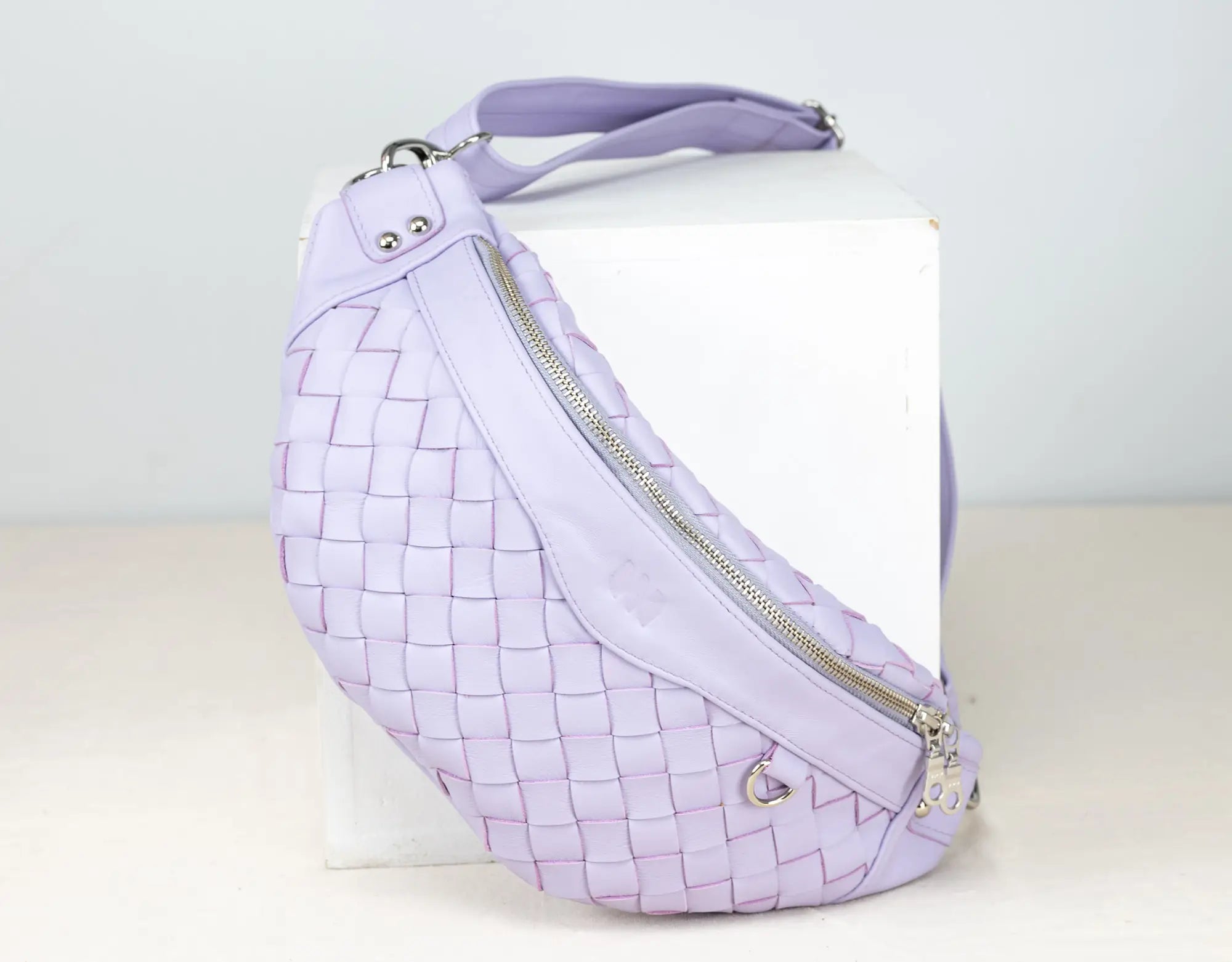 Lavender woven handbag with a white card inside on a light gray background