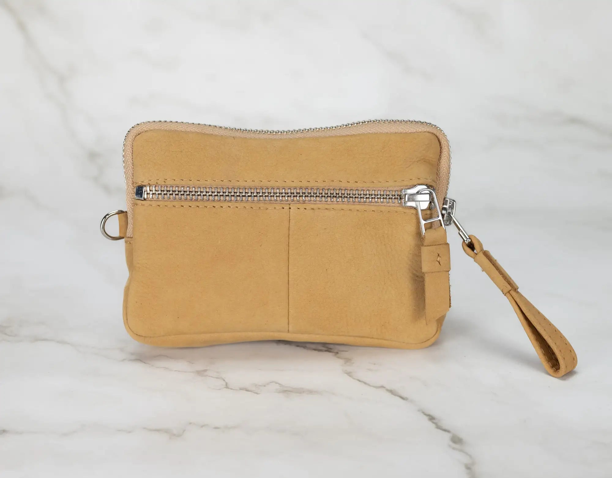 Beige wristlet with a zipper on a marble surface