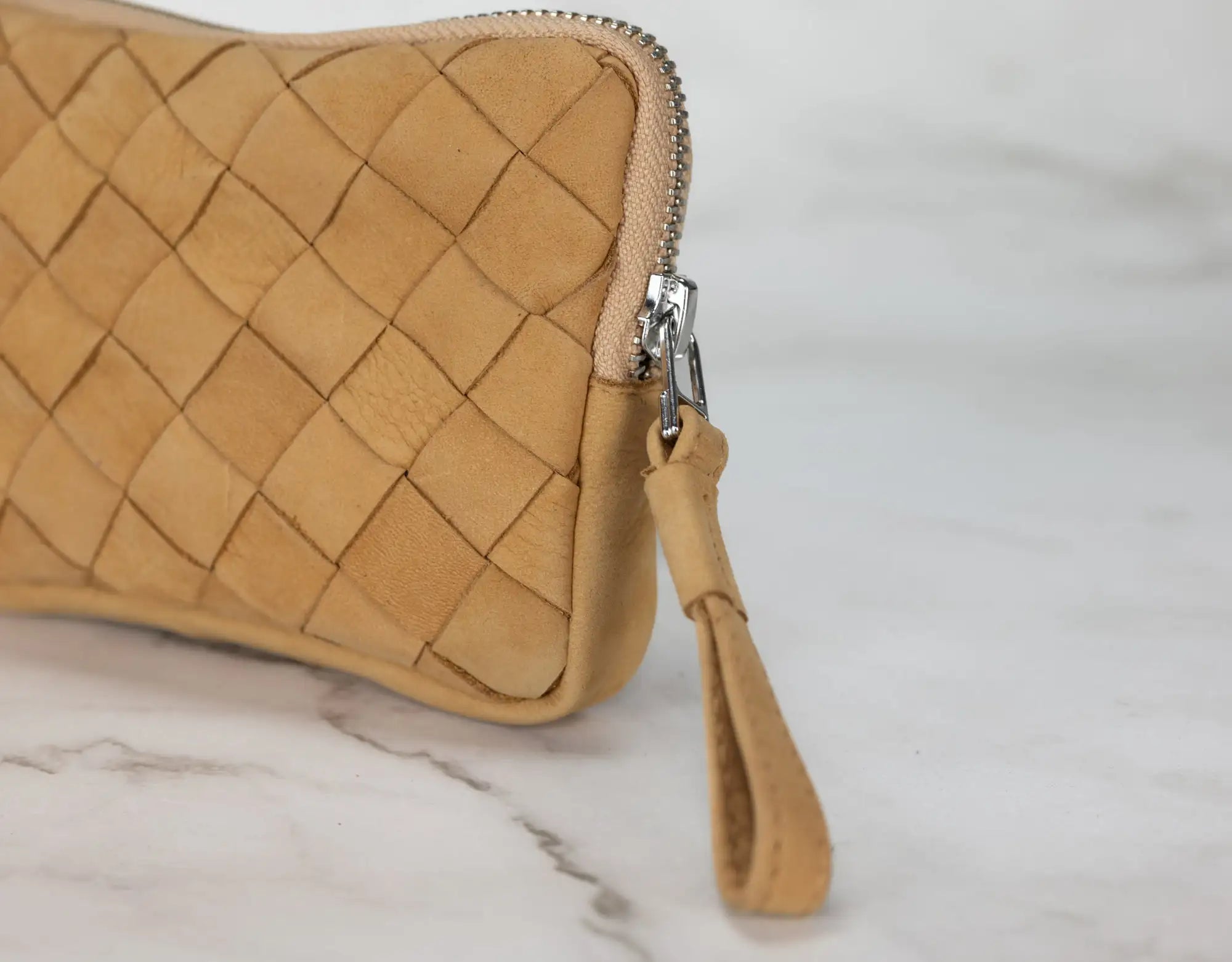 Tan woven clutch bag on a marble surface