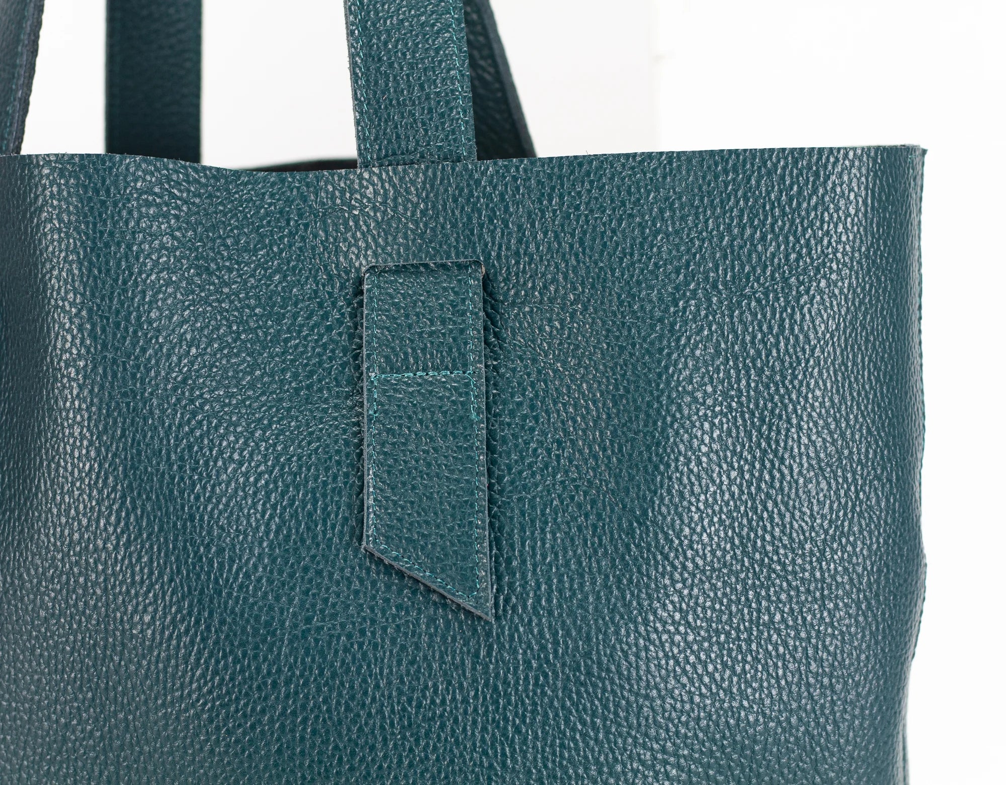 Teal leather tote bag with a pocket on a white background