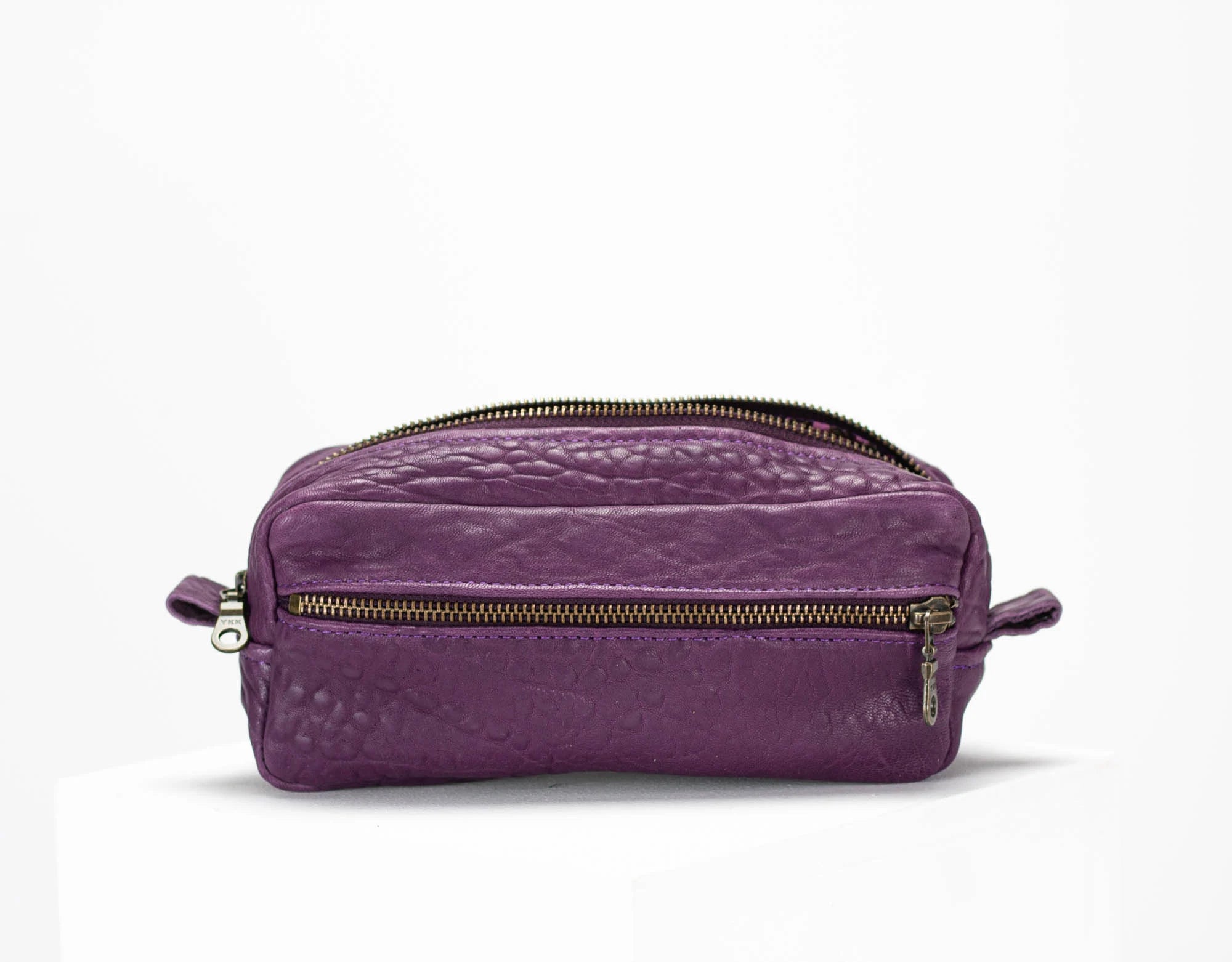 Purple leather dopp kit with gold zipper on a white background
