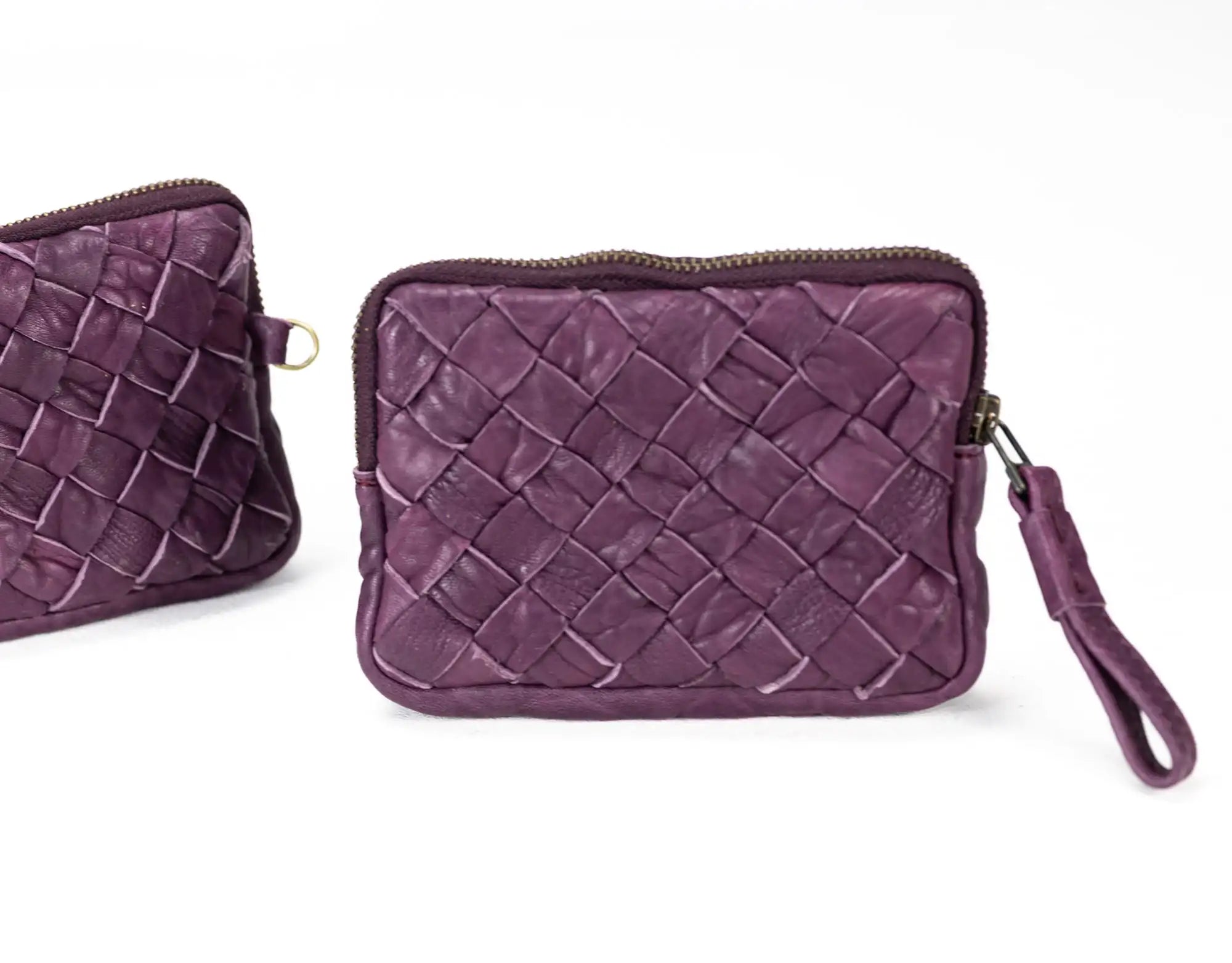 Purple woven clutch bag with a strap on a white background