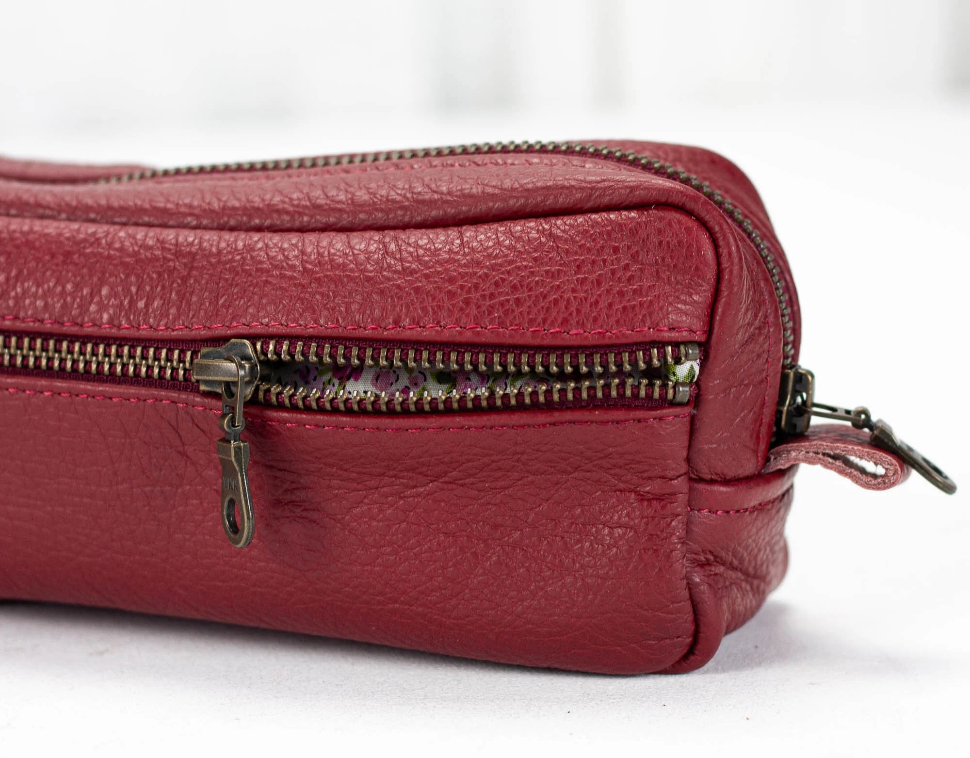 Red leather bag with multiple zippers on a white background