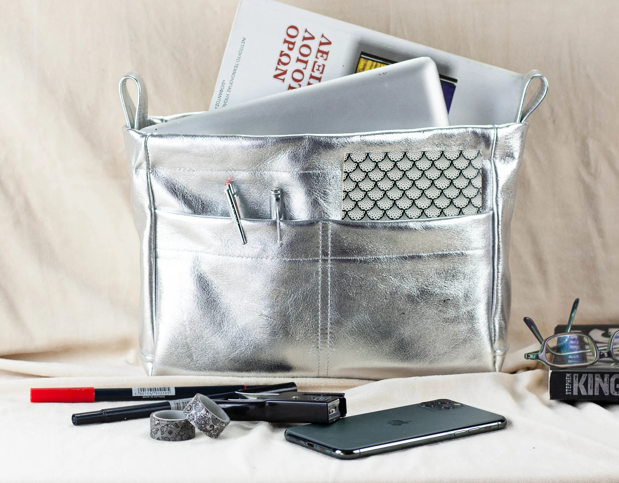 Silver bag insert with compartments on a beige surface