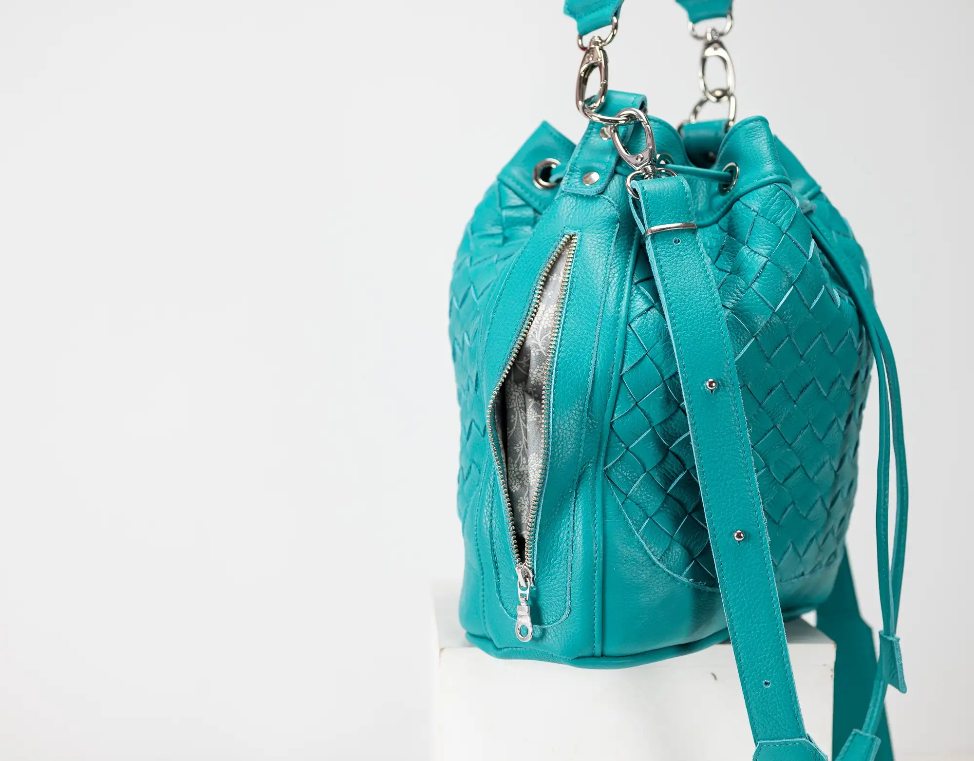 Turquoise woven leather bucket bag on a white background