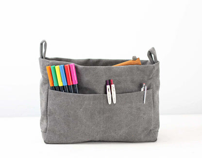 Gray fabric bag insert with colorful markers and clothespins on a white background
