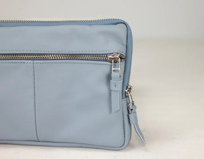 Light blue leather bag with zippers on a light gray background