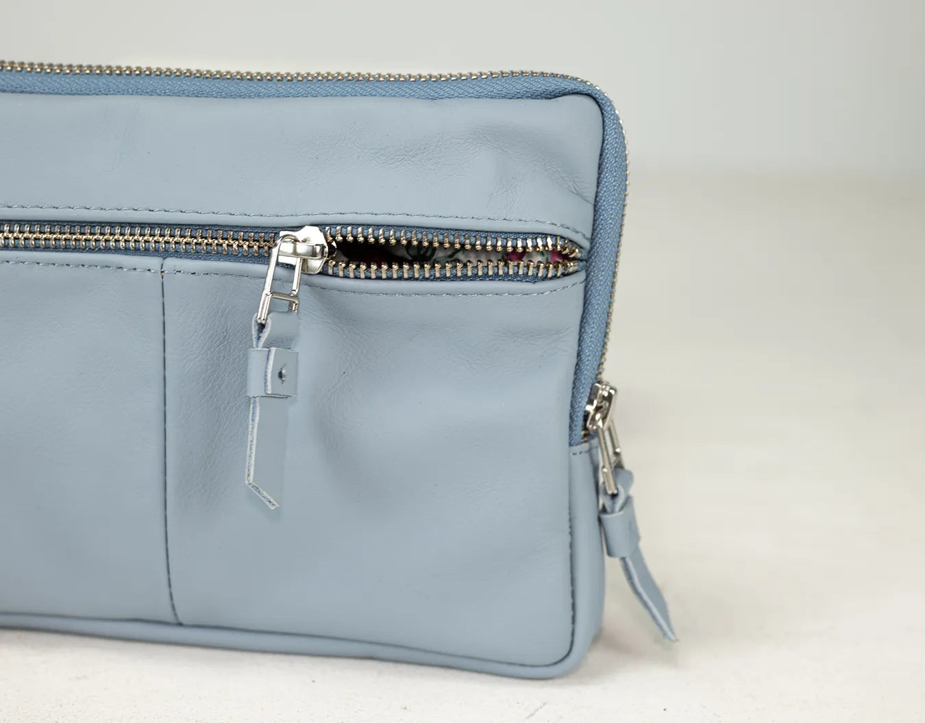 Light blue handbag with zippers on a light background