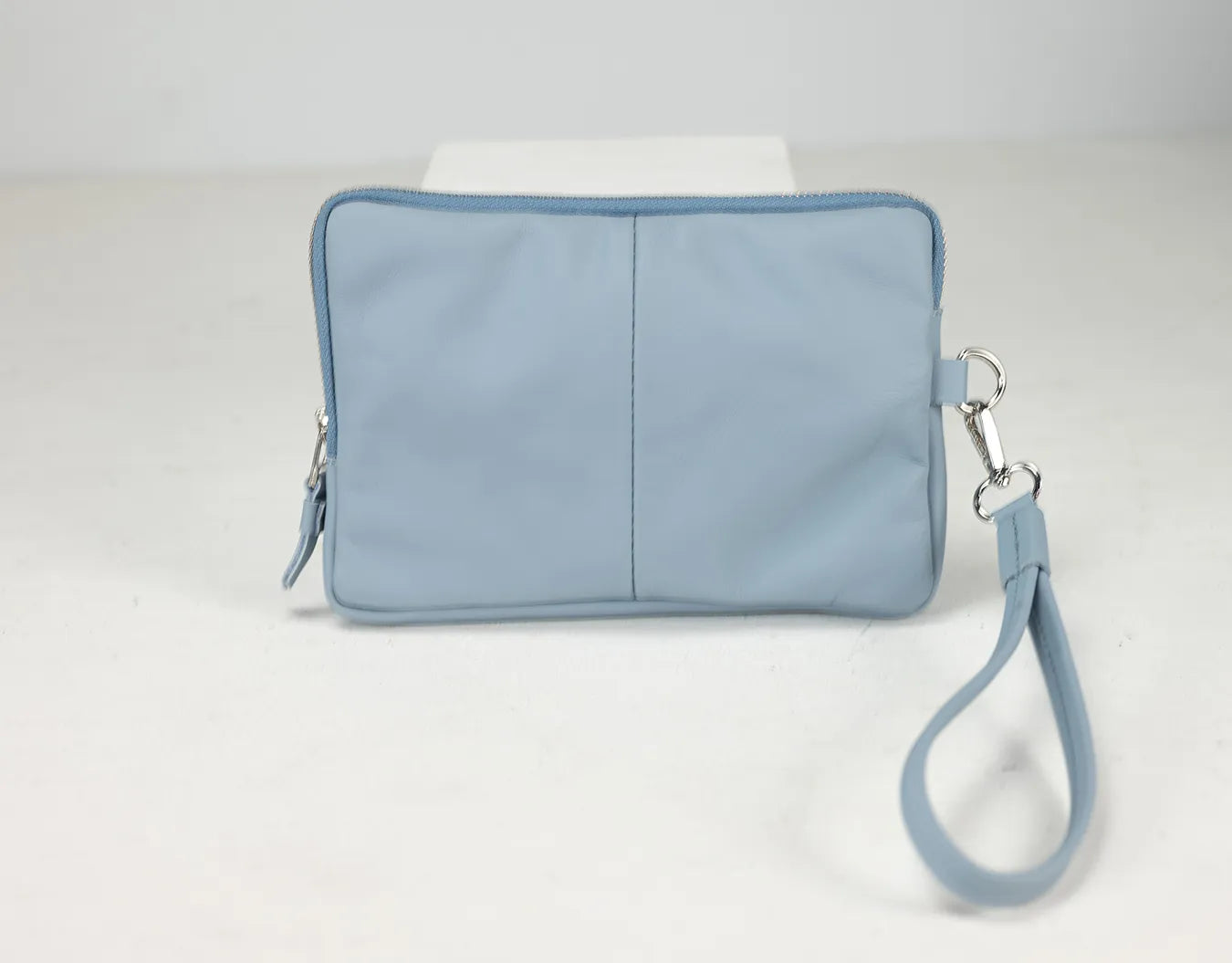 Light blue wristlet bag with a strap on a white background
