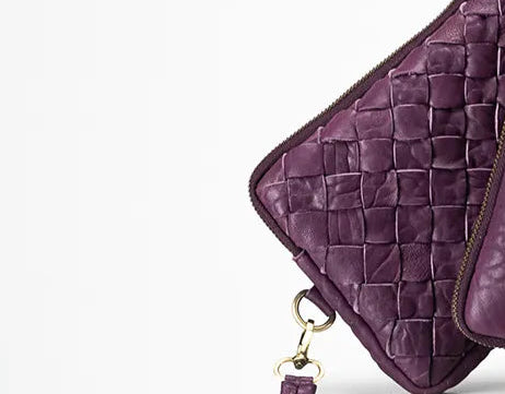 Purple woven leather clutch with a strap on a white background