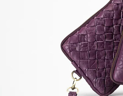 Purple woven leather clutch with a strap on a white background