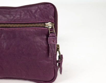 Purple leather bag with gold zipper on a white background
