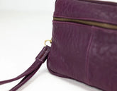 Purple leather bag with a gold zipper on a white background