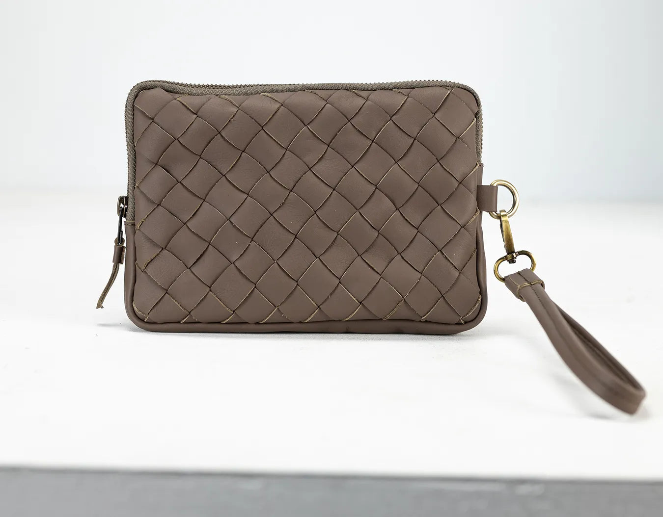 Brown woven clutch bag with a strap on a white background