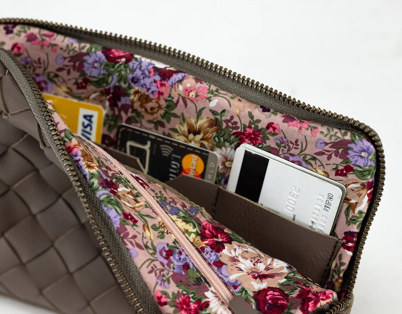 Floral-patterned pouch with a phone and cards inside on a white background
