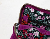 Floral-patterned bag with a purple zipper on a light background