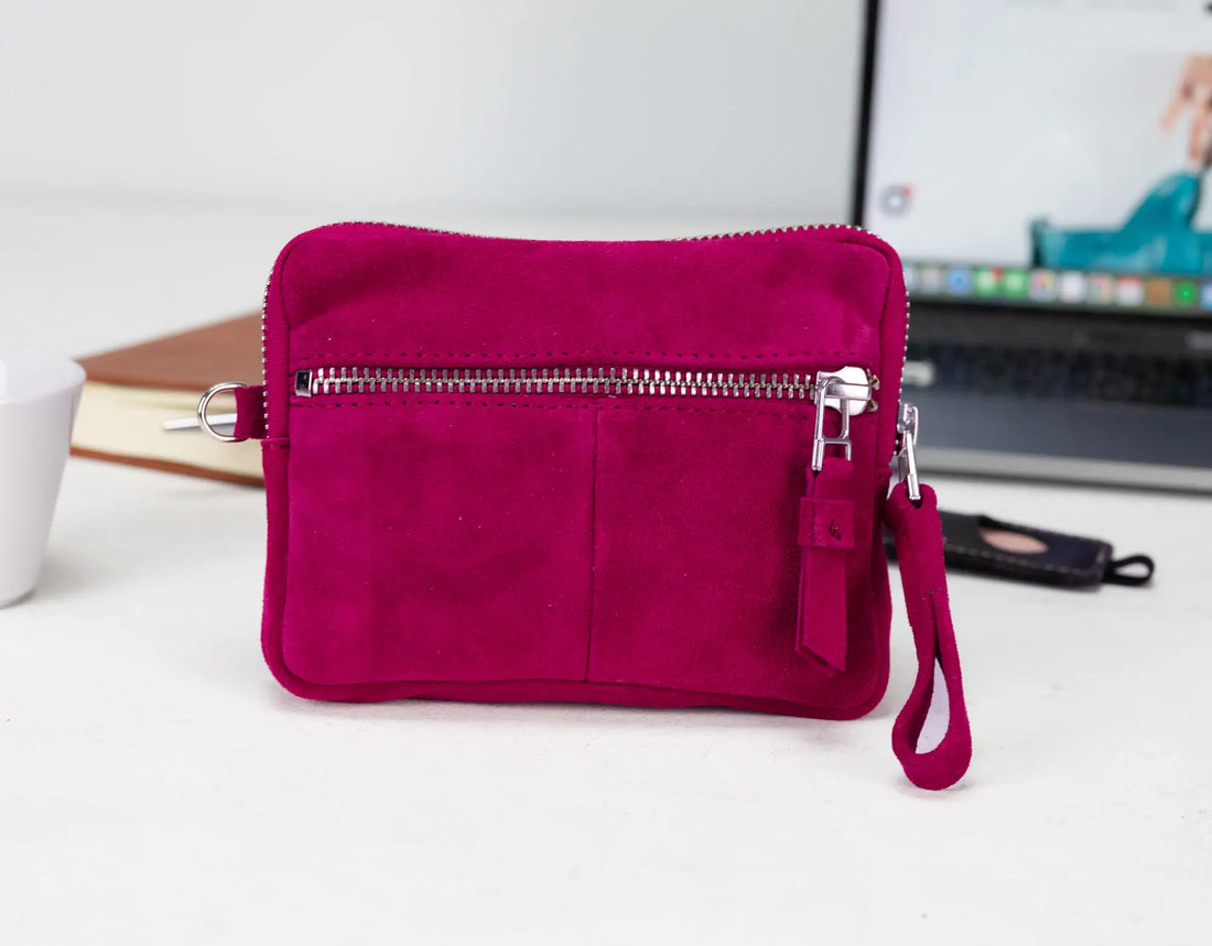 Pink clutch bag with a zipper on a white surface