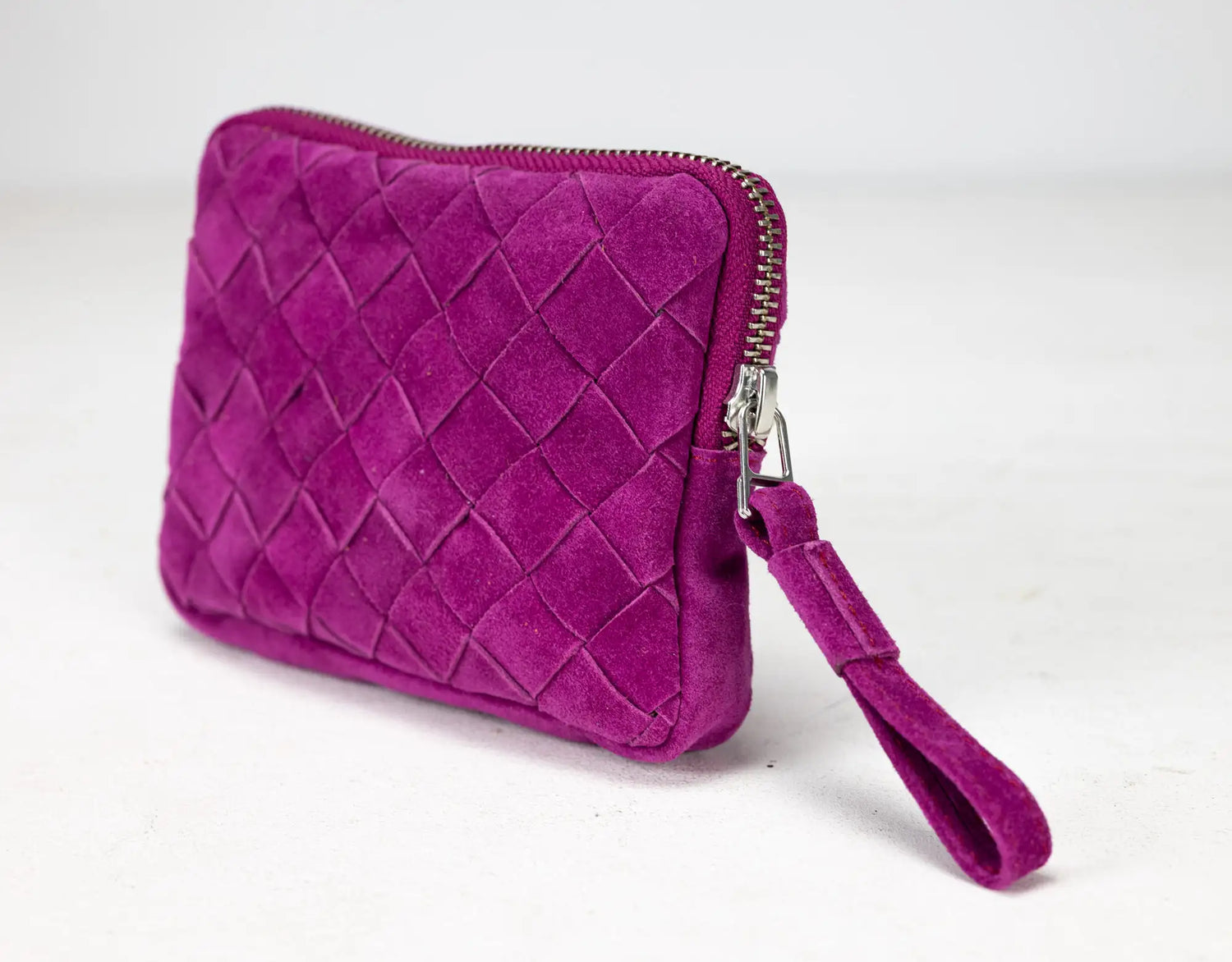 Purple quilted clutch bag with a wrist strap on a white background