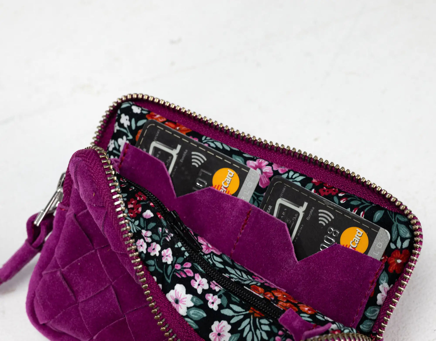 Purple wallet with floral pattern open to reveal cards on a white background