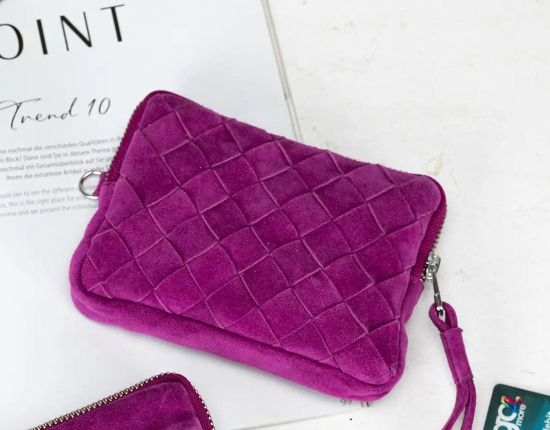 Two purple handbags on a white surface with keys and cards beside them.