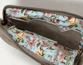 Floral patterned clutch bag with a zipper on a neutral background