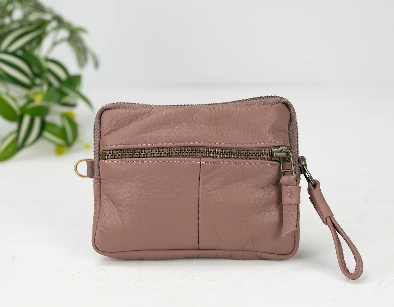 old rose leather wristlet with a zipper on a white background