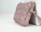 Pink quilted clutch bag with a silver zipper on a light gray background
