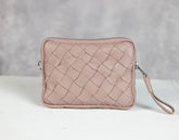 Pink woven clutch bag on a white surface with a gray background