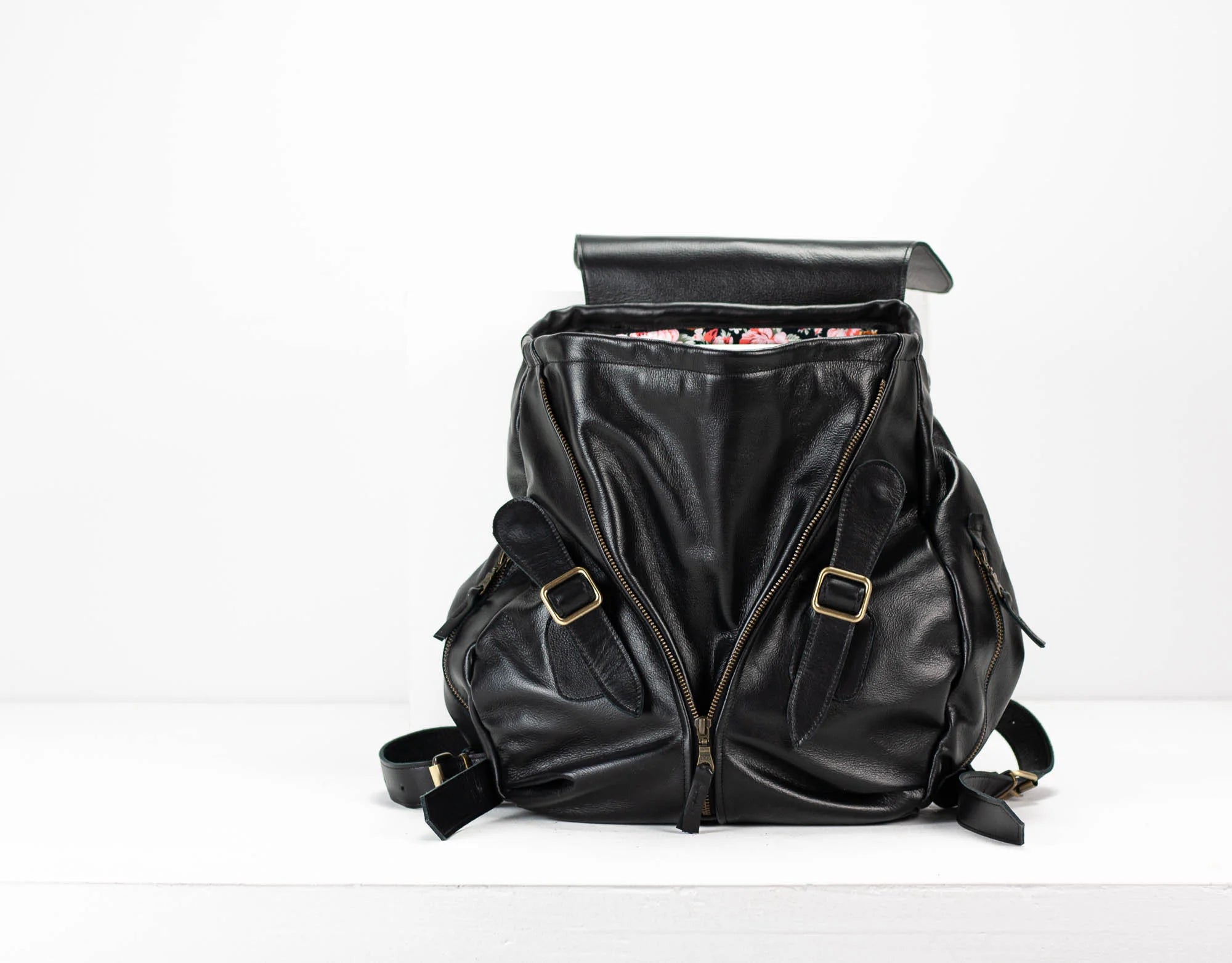 Black leather backpack with gold buckles on a white background