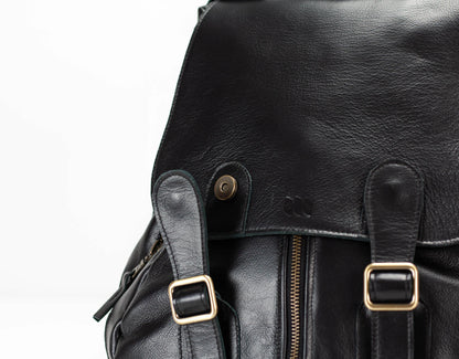 Close-up of a black leather backpack with gold buckles on a white background