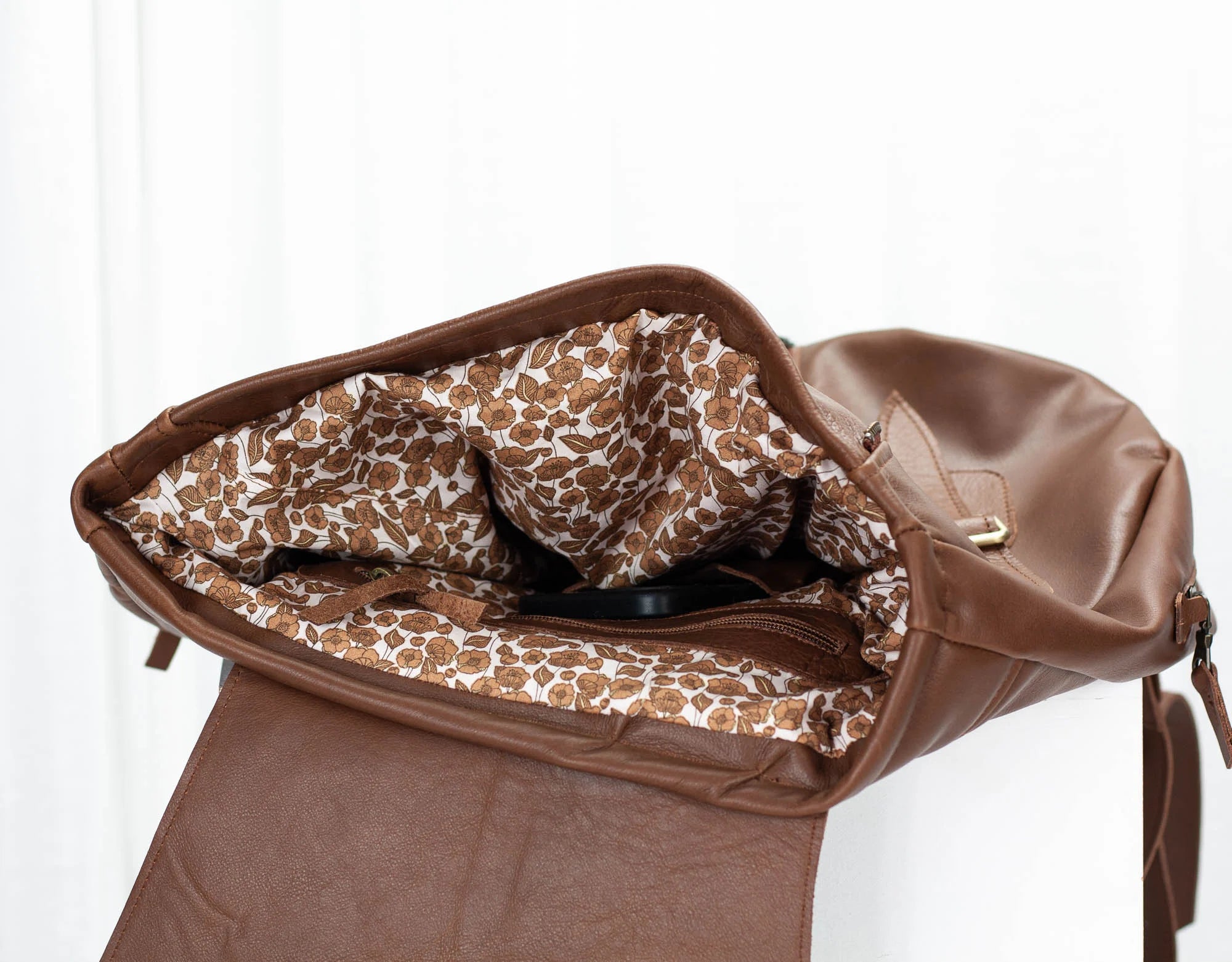 Brown leather bag with floral lining on a white background