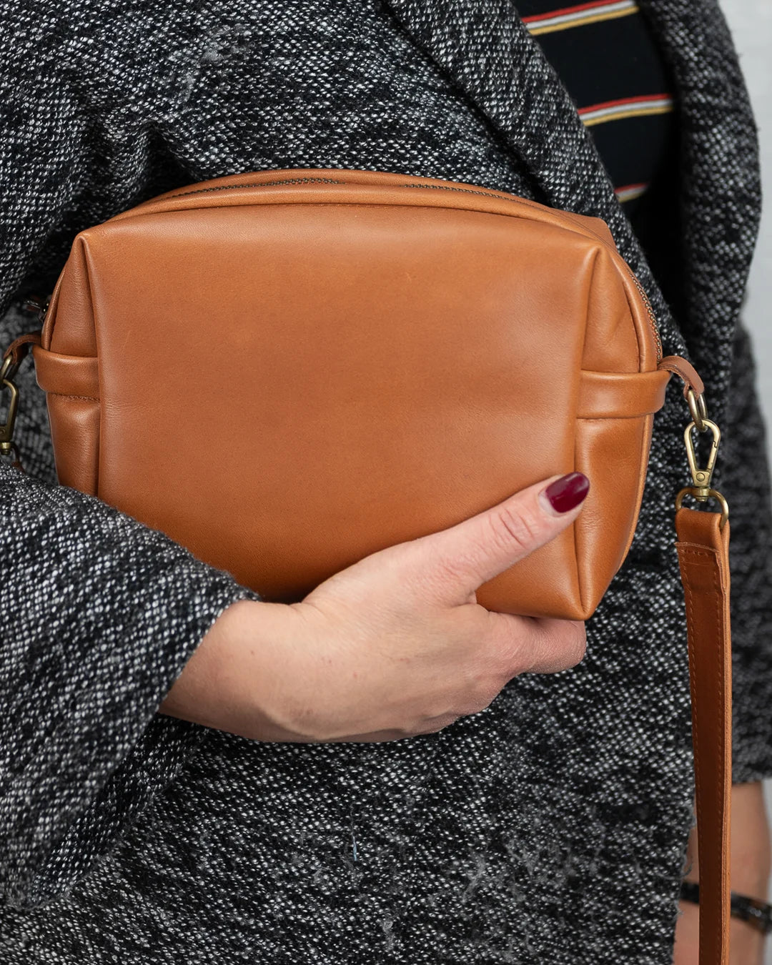 Person holding a brown leather bag with a blurred background