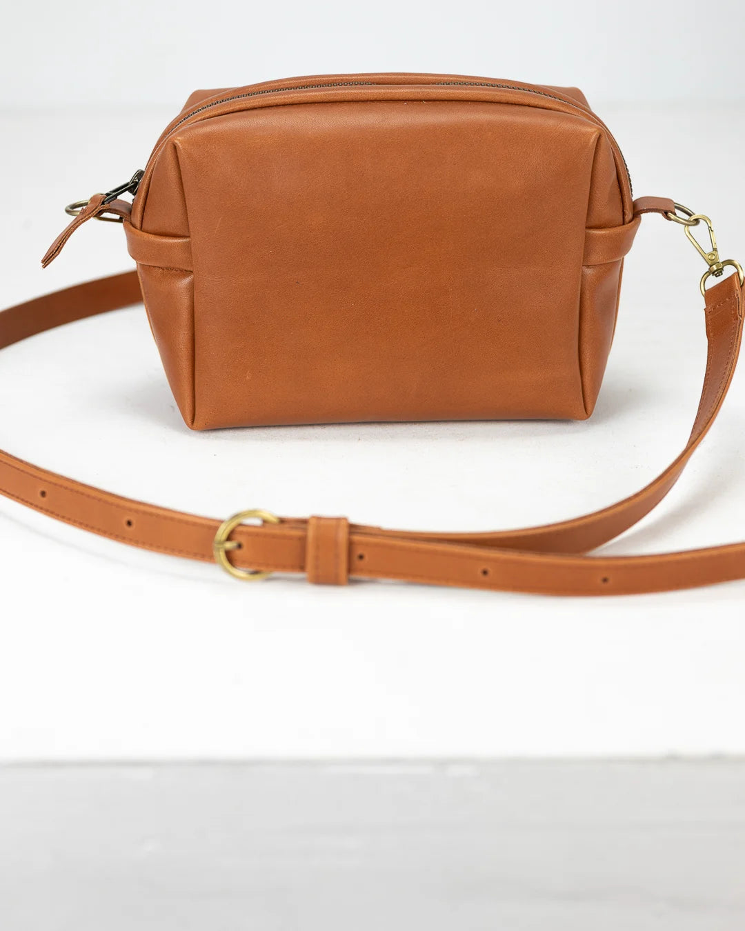 Brown leather bag with a strap on a white background