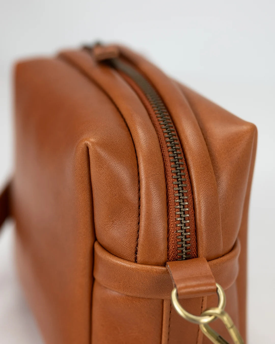 Brown leather bag with a gold zipper on a white background