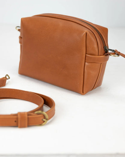 Brown leather handbag with matching strap on a white background